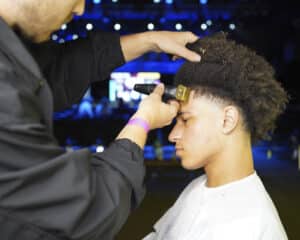 Model having his hair cut by barber on the Dense stand at HairCon 2024.